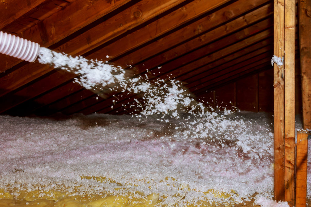 Worker Spraying mineral rock wool of house attic insulation
